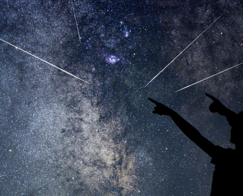 Un ciel avec des étoiles filantes et deux personnes silhouettées qui les regardent