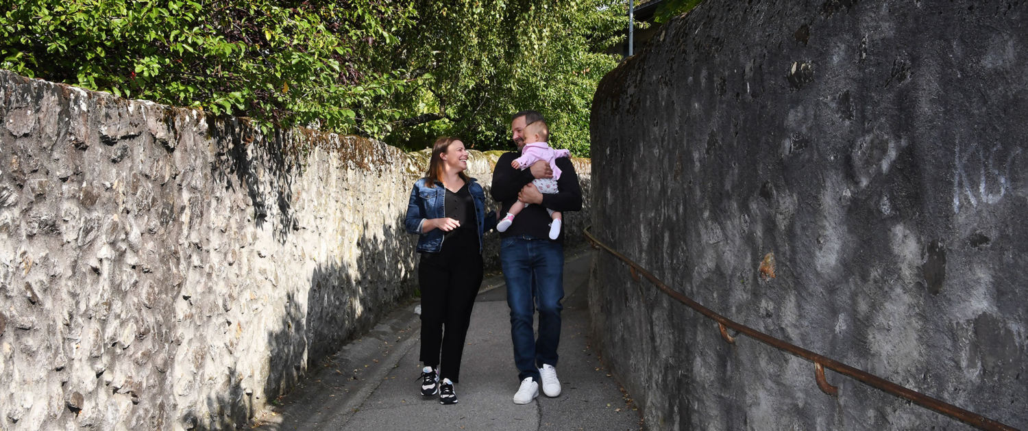 Un jeune couple souriant et complice avec un bébé marche sur le sentier de Pévret.